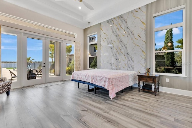 bedroom with french doors, wood finished floors, an accent wall, and access to outside