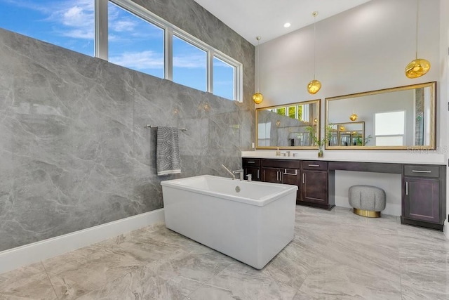 full bathroom featuring marble finish floor, recessed lighting, a high ceiling, a freestanding bath, and vanity