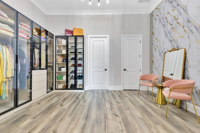 bedroom featuring baseboards, wood finished floors, visible vents, and ornamental molding