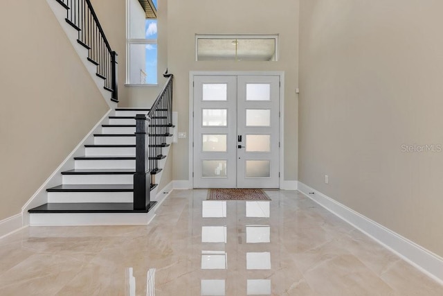 entrance foyer with baseboards, stairs, french doors, a towering ceiling, and marble finish floor