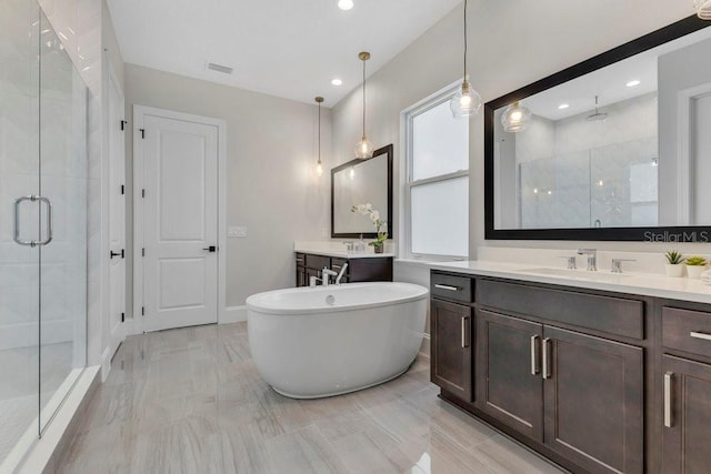 bathroom featuring visible vents, two vanities, a sink, a shower stall, and a freestanding bath