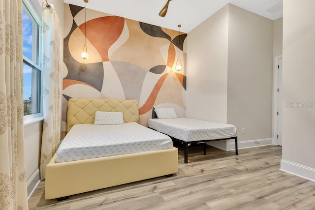 bedroom with multiple windows, baseboards, and wood finished floors