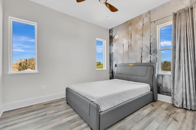 bedroom with ceiling fan, baseboards, and wood finished floors