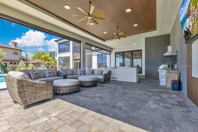 view of patio featuring ceiling fan, fence, an outdoor hangout area, an outdoor kitchen, and a sink