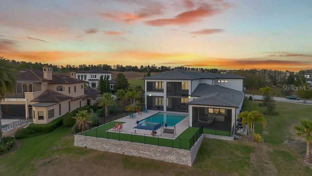 back of property at dusk with a patio, a fenced in pool, a yard, a fenced backyard, and a residential view