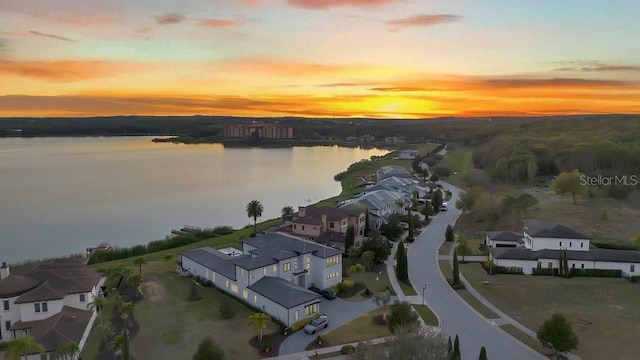 aerial view at dusk featuring a residential view and a water view