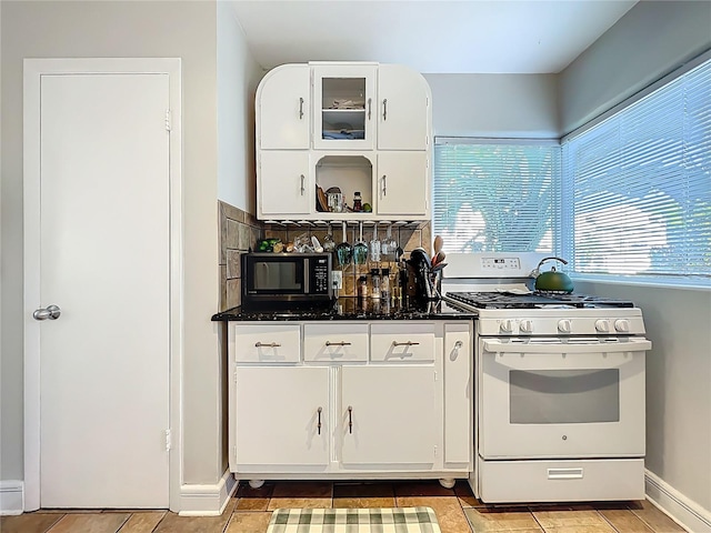 kitchen with tasteful backsplash, white cabinetry, black microwave, and gas range gas stove