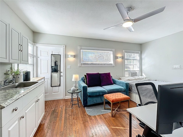 living room featuring a textured ceiling, light wood-type flooring, and ceiling fan