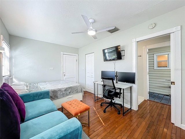 bedroom featuring visible vents, dark wood-style flooring, ceiling fan, a closet, and a textured ceiling