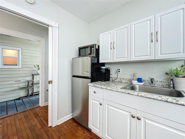 kitchen with dark wood finished floors, a sink, light countertops, appliances with stainless steel finishes, and white cabinetry