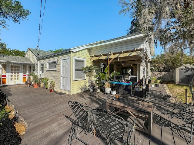 wooden deck with an outdoor structure, fence, and a shed