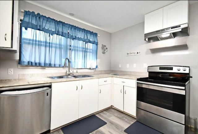 kitchen with a sink, under cabinet range hood, stainless steel appliances, white cabinets, and light countertops