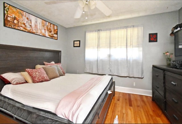 bedroom featuring baseboards, a ceiling fan, and light wood finished floors