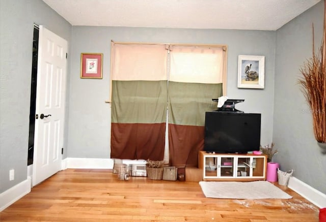 rec room with baseboards, a textured ceiling, and wood finished floors