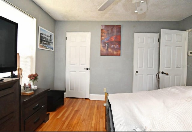 bedroom with light wood-style flooring, a ceiling fan, and baseboards