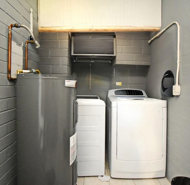 clothes washing area featuring light tile patterned flooring, laundry area, independent washer and dryer, and electric water heater