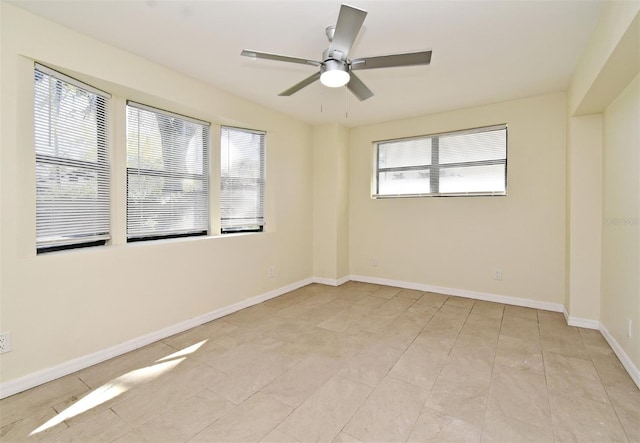 spare room with light tile patterned floors, a healthy amount of sunlight, a ceiling fan, and baseboards