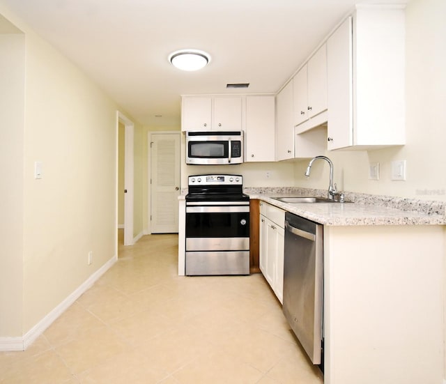 kitchen featuring a sink, stainless steel appliances, baseboards, and white cabinetry