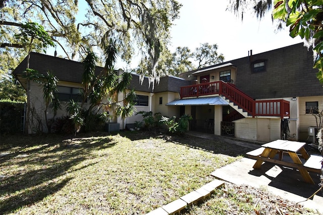 back of property with stairway, a patio, roof with shingles, and a deck