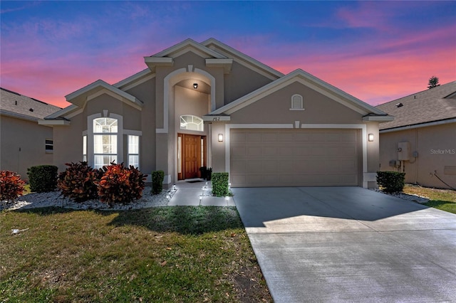 view of front facade featuring a yard, a garage, driveway, and stucco siding