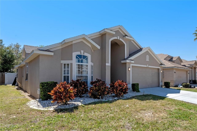 view of front of property with stucco siding, a front yard, concrete driveway, and an attached garage