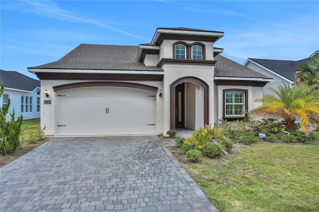 view of front of home featuring an attached garage, stucco siding, decorative driveway, and a front yard