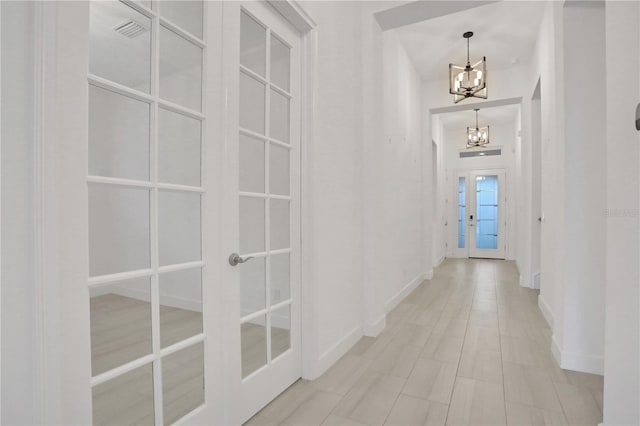 corridor featuring an inviting chandelier, baseboards, french doors, and visible vents