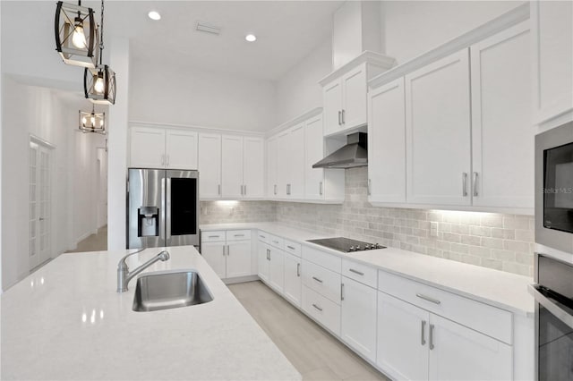 kitchen featuring wall chimney range hood, white cabinets, appliances with stainless steel finishes, a sink, and light countertops