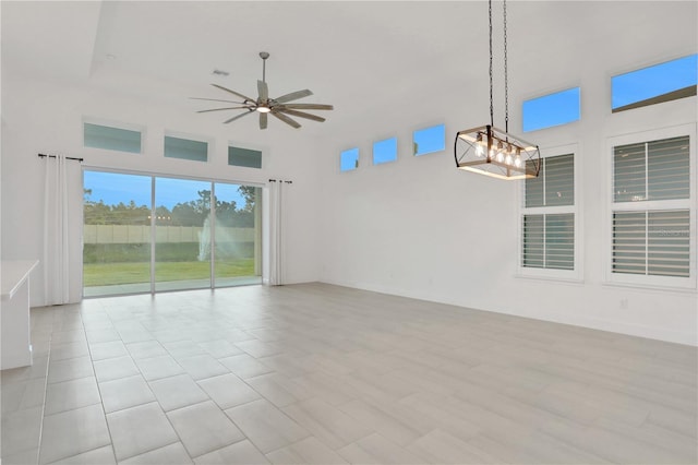unfurnished room featuring ceiling fan with notable chandelier and a towering ceiling