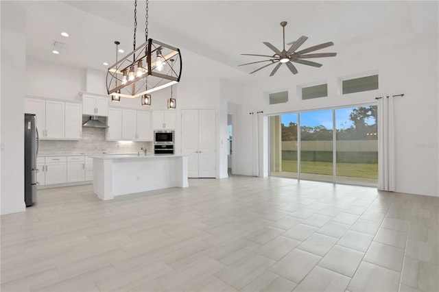 kitchen featuring under cabinet range hood, stainless steel appliances, a high ceiling, and open floor plan