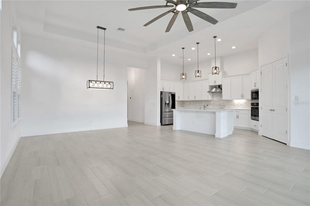 unfurnished living room featuring ceiling fan, visible vents, a towering ceiling, a raised ceiling, and recessed lighting