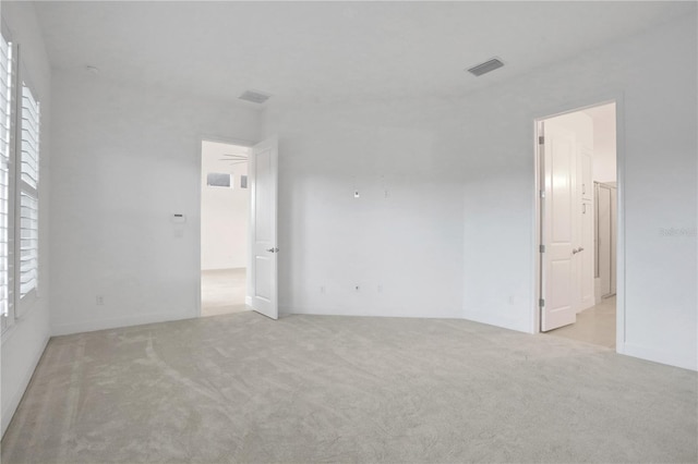 empty room featuring plenty of natural light, carpet, and visible vents