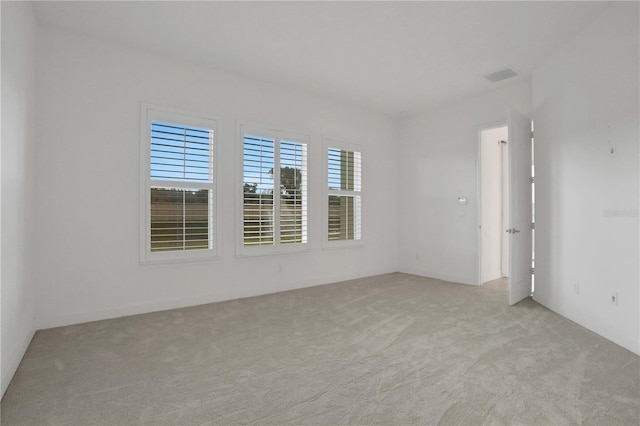 empty room featuring visible vents and light colored carpet
