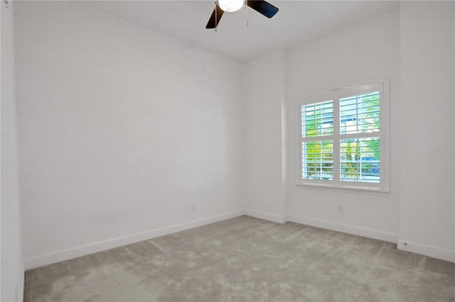 empty room with baseboards, a ceiling fan, and light colored carpet