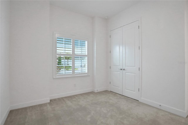 unfurnished bedroom featuring baseboards, carpet, and a closet