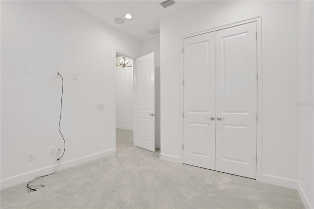 unfurnished bedroom with light colored carpet, baseboards, visible vents, and a closet