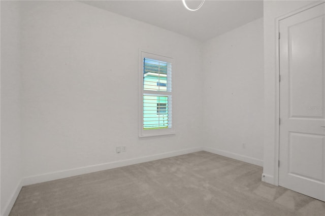 empty room featuring baseboards and light carpet