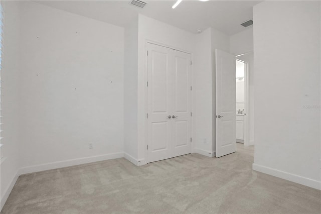 unfurnished bedroom featuring baseboards, light carpet, and visible vents