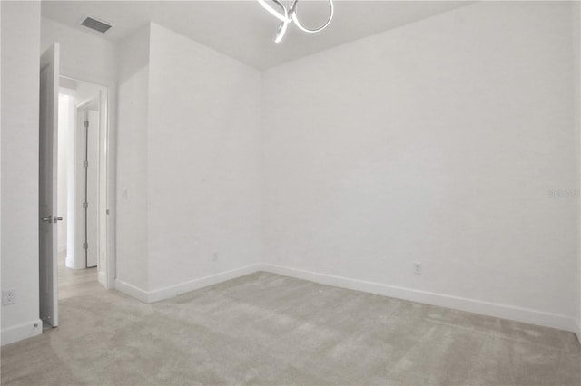 empty room featuring baseboards, light carpet, and visible vents