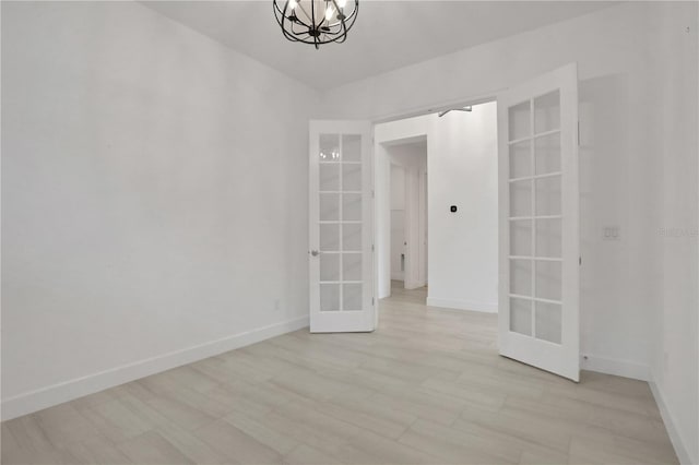 spare room with light wood-style floors, baseboards, french doors, and a notable chandelier