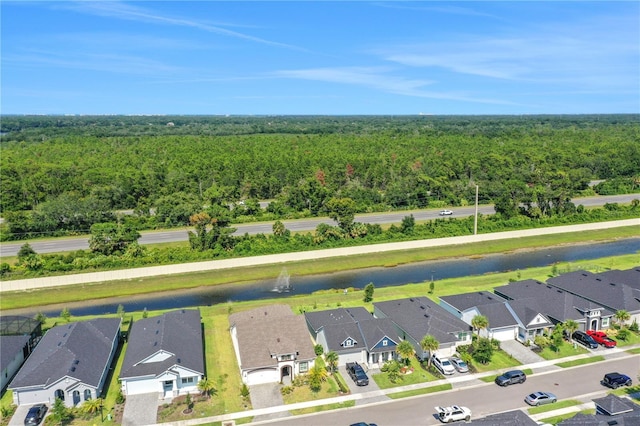 drone / aerial view featuring a forest view, a water view, and a residential view