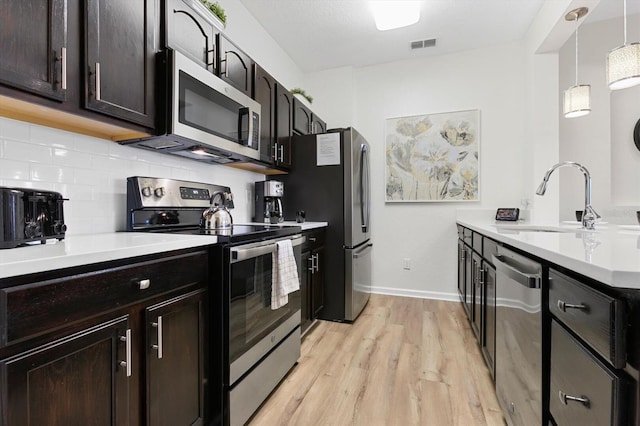 kitchen featuring visible vents, backsplash, light wood-style floors, stainless steel appliances, and a sink