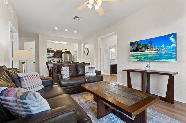 living room featuring light wood-type flooring, visible vents, a ceiling fan, recessed lighting, and baseboards