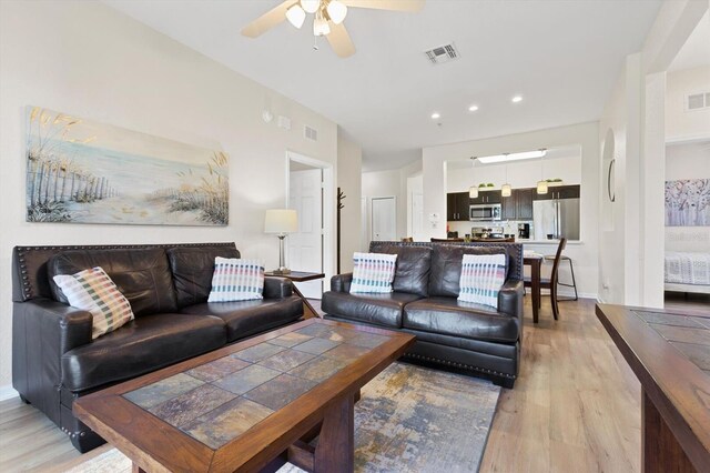 living area featuring visible vents, light wood-style flooring, and a ceiling fan