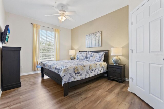 bedroom with light wood-style floors, baseboards, and ceiling fan