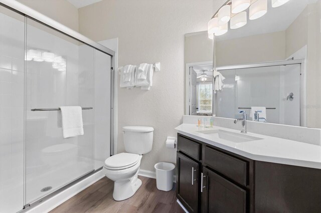 full bath with a shower stall, toilet, vanity, and wood finished floors