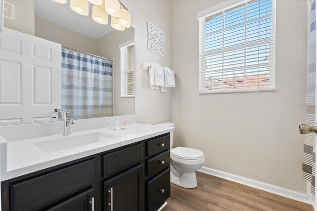 full bathroom with vanity, wood finished floors, baseboards, curtained shower, and toilet