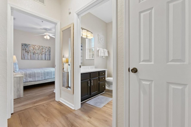 bathroom featuring vanity, toilet, wood finished floors, and ensuite bathroom