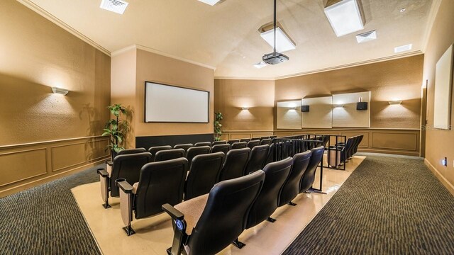 cinema room featuring crown molding, a decorative wall, and visible vents