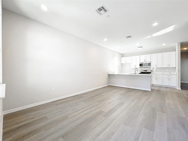 unfurnished living room with baseboards, visible vents, recessed lighting, a sink, and light wood-type flooring